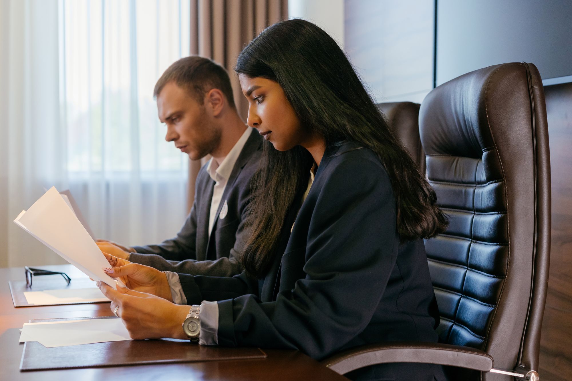 Two professionals reviewing documents together at an office table.